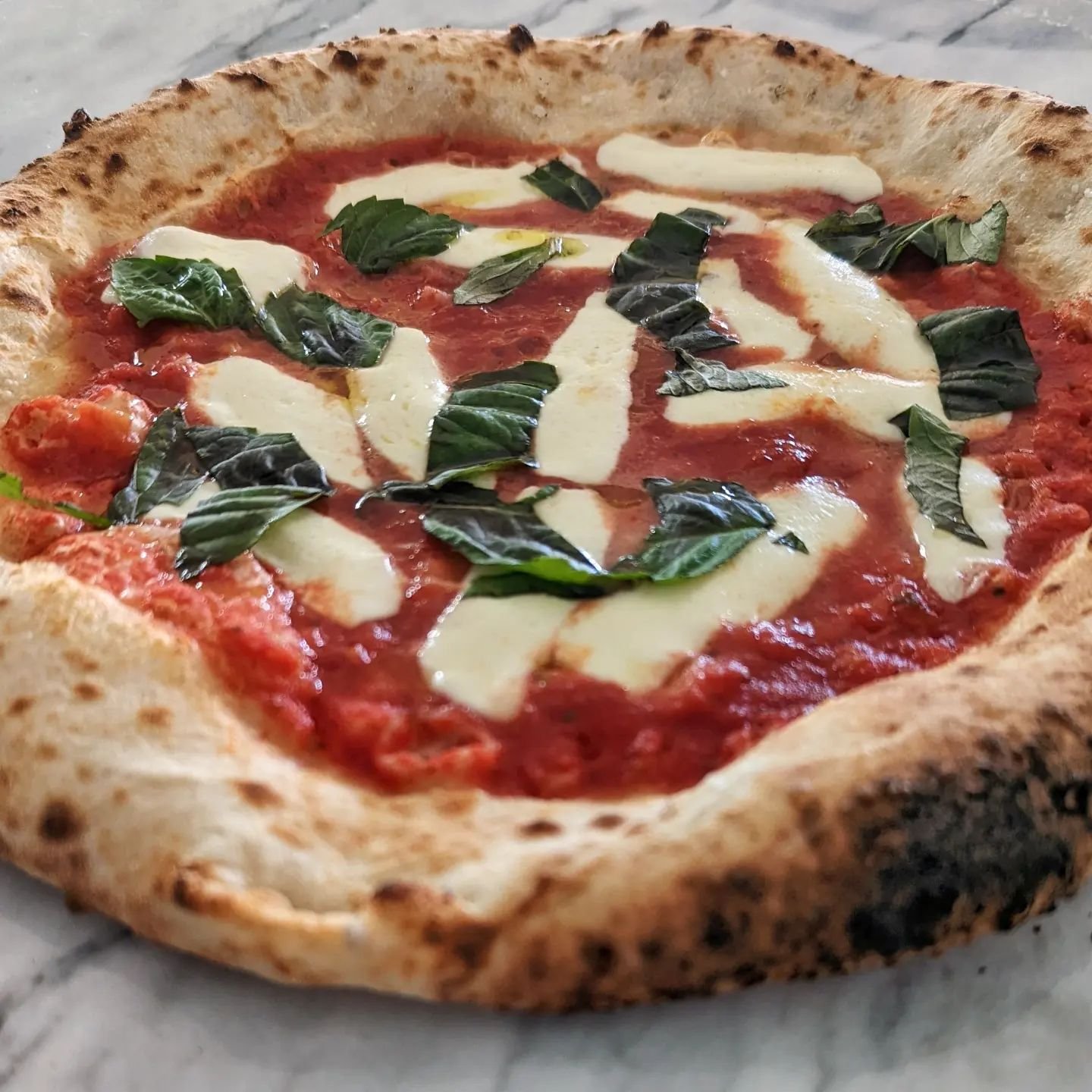 Wood fired pizza on a marble table top.