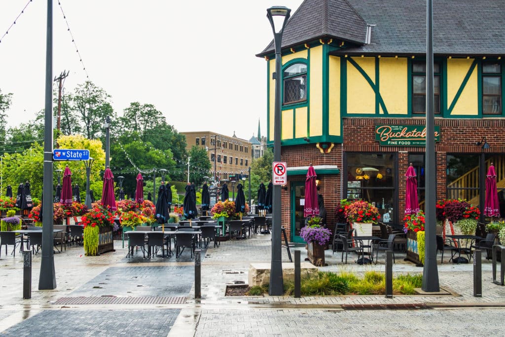 The Village of Wauwatosa with Buckatabon in the background, outdoor seating, trees and street lamps. 